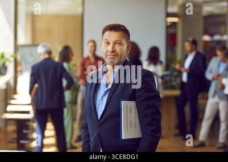 Uomo d'affari maturo e fiducioso che guarda la fotocamera in ufficio. Foto Stock