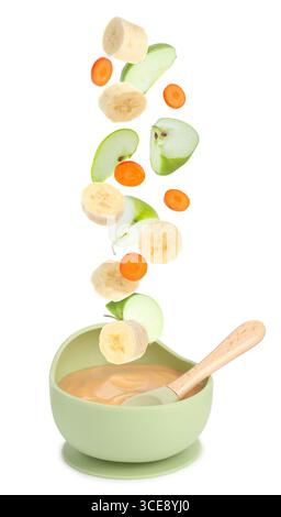 Cibo per bambini. Fette di mela, banana e carota che cadono nel recipiente della purea su sfondo bianco Foto Stock
