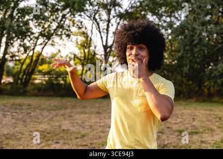Giovane che mostra sorpresa e copre bocca nel parco Foto Stock