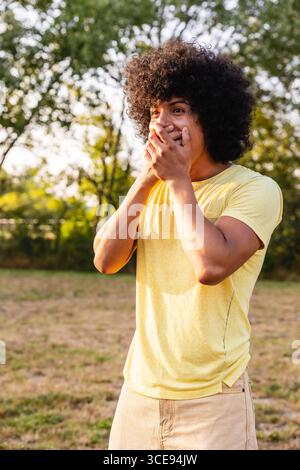 Giovane che si copre la bocca con stupore in un parco Foto Stock