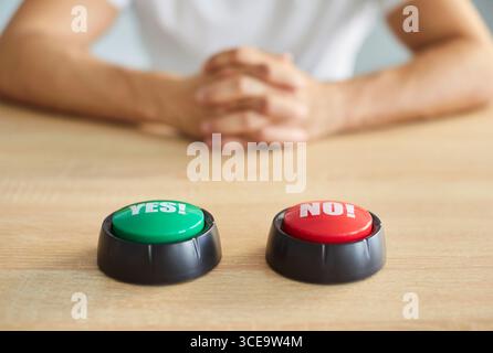SÌ e NO pulsanti sul tavolo con l'uomo seduto sullo sfondo che prende decisioni e scelte Foto Stock