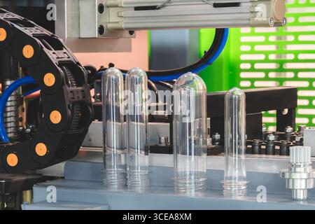 Preforme in plastica PETG per la produzione di bottiglie sul nastro trasportatore prima della pressa per soffiaggio a caldo Foto Stock