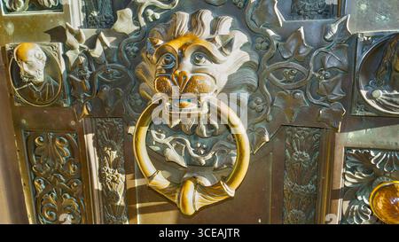 Porta a forma di leone con un massiccio anello in metallo, dettaglio vintage su una vecchia porta in legno Foto Stock