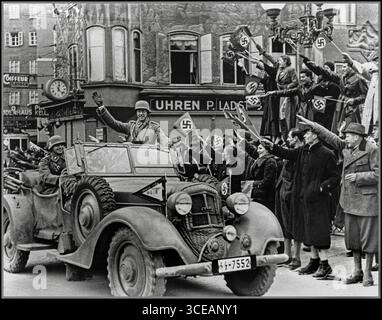 ANSCHLUSS AUSTRIA SALISBURGO i cittadini austriaci salutano e sventolano felicemente le bandiere della svastica mentre i soldati della 2a divisione Panzer tedesca "Das Reich" attraversano Salisburgo a bordo di un Horch 830 R Kübelwagen. L'evento ebbe luogo poco dopo che Adolf Hitler annunciò l'Anschluss, segnando l'annessione dell'Austria alla Germania nazista il 12 marzo 1938. Foto Stock