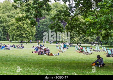 Persone che si rilassano sull'erba in un Royal London Park, sdraio e vegetazione Foto Stock