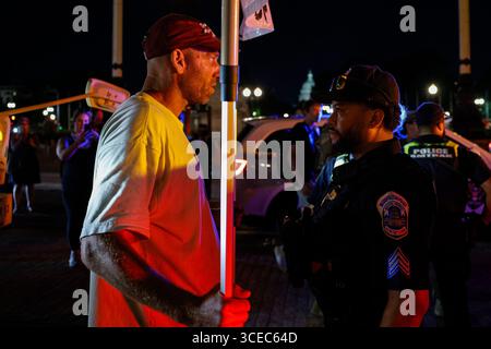 Washington, District of Columbia, USA. 16 agosto 2025. Un manifestante si trova di fronte a un veicolo militare mentre un ufficiale della polizia metropolitana lo avverte di lasciare vicino alla Union Station il 16 agosto 2025, a Washington, il presidente Donald Trump ha annunciato i piani per dispiegare gli ufficiali federali e la Guardia Nazionale nel distretto, con l'obiettivo di porre il Dipartimento di polizia metropolitana di Washington sotto il controllo federale e assistere gli sforzi di prevenzione del crimine nella capitale della nazione. Crediti: ZUMA Press, Inc./Alamy Live News Foto Stock