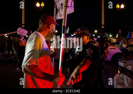 Washington, District of Columbia, USA. 16 agosto 2025. Un manifestante si trova di fronte a un veicolo militare mentre un ufficiale della polizia metropolitana lo avverte di lasciare vicino alla Union Station il 16 agosto 2025, a Washington, il presidente Donald Trump ha annunciato i piani per dispiegare gli ufficiali federali e la Guardia Nazionale nel distretto, con l'obiettivo di porre il Dipartimento di polizia metropolitana di Washington sotto il controllo federale e assistere gli sforzi di prevenzione del crimine nella capitale della nazione. Crediti: ZUMA Press, Inc./Alamy Live News Foto Stock