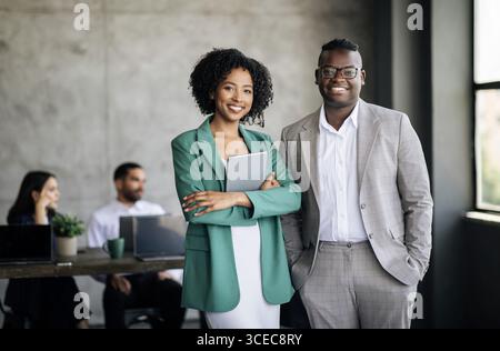 Felice coppia di colleghi neri in posa al Modern Office Interior Foto Stock