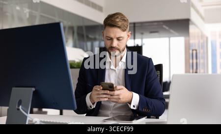 Giovane CEO concentrato che utilizza la moderna tecnologia Internet sul posto di lavoro Foto Stock