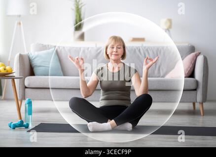 Serena calma contented felice matura donna europea meditating in soggiorno interno in bolla protettiva Foto Stock