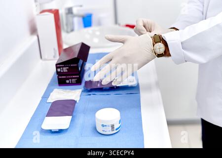 Primo piano di un professionista medico maschile che indossa guanti protettivi. Medico che indossa guanti protettivi in clinica Foto Stock