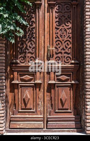 Una porta di legno splendidamente intagliata a Tbilisi, caratterizzata da motivi ornati e dettagli artigianali. La porta mette in risalto il fascino e la storia del ci Foto Stock