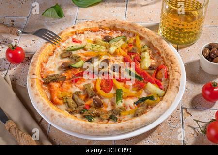 Una vivace pizza vegetariana condita con verdure fresche colorate, tra cui peperoni rossi e gialli, zucchine e olive, servita su un forno perfetto Foto Stock