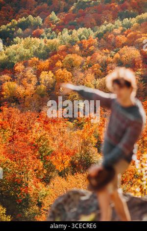 Un uomo si erge tra il vivace fogliame autunnale di Quebec, Canada, e si gode l'incredibile varietà di foglie rosse, arancioni e gialle. La stagione autunnale è iniziata Foto Stock