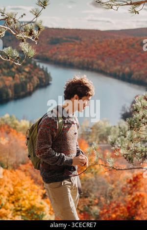 Una persona gode di un'escursione tranquilla in Quebec, Canada, durante l'autunno. Il vivace fogliame autunnale circonda un fiume calmo, che illustra la natura della stagione Foto Stock