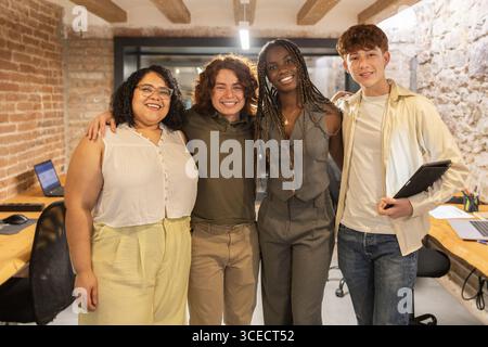 Un gruppo diversificato di giovani professionisti in uno spazio di coworking, che abbraccia il lavoro di squadra e la collaborazione con la tecnologia, mostrando un ambiente di lavoro inclusivo Foto Stock