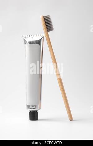 Spazzolino in bambù ecologico con un tubo per dentifricio elegante, su uno sfondo bianco minimalista. Ideale per livi di rifiuti sostenibili e senza sprechi Foto Stock