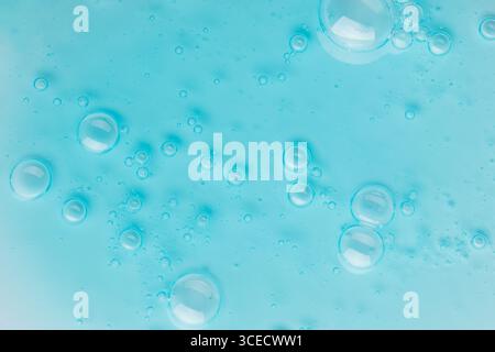 Vista ravvicinata delle gocce di gel cosmetico blu sparse su una superficie liscia. L'immagine cattura la consistenza e la nitidezza delle bolle di gel, con una vibra Foto Stock