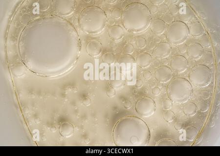 Immagine ravvicinata che cattura l'intricata consistenza di bolle d'olio sospese su una superficie in vetro traslucido. La prospettiva macro evidenzia l'interazione Foto Stock