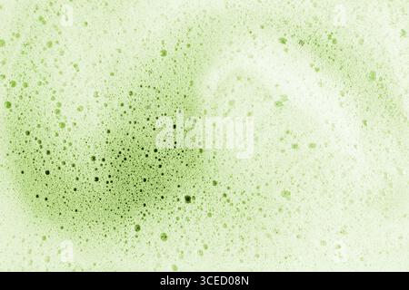 Primo piano di una delicata schiuma matcha, che mostra la sua trama intricata e le rinfrescanti tonalità verdi. La superficie rivela bolle di varie dimensioni, cre Foto Stock