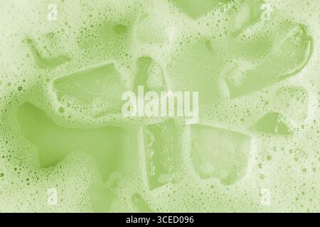 Immagine ravvicinata di matcha freddo ghiacciato che mostra una consistenza spumeggiante e cubetti di ghiaccio. Le bolle di superficie della bevanda rinfrescante catturano un senso di Foto Stock