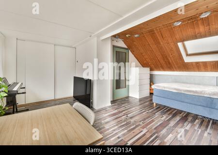 Una camera moderna ben illuminata con mobili eleganti, pavimento in legno e un'estetica minimalista perfetta per il relax o il lavoro. Foto Stock