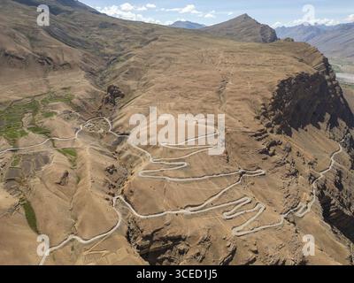 Una splendida vista aerea cattura le tortuose strade della Spiti Valley, India, mostrando il terreno accidentato e montuoso e le zone verdi contrastanti ami Foto Stock