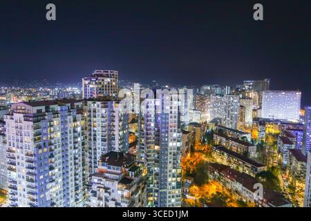 Una splendida vista notturna di Batumi, Georgia, che mostra alti edifici illuminati e strade vivaci. Lo skyline è sullo sfondo di Foto Stock