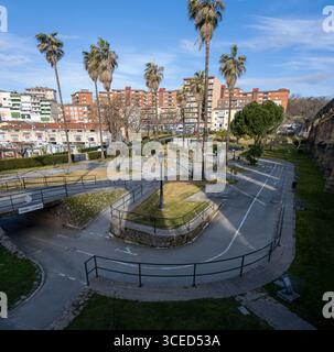Parco urbano per lezioni di guida con sentieri tortuosi, palme ed edifici residenziali. Foto Stock