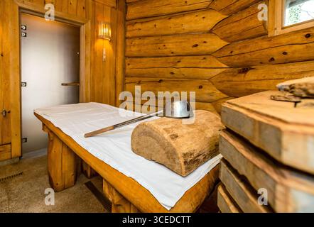 Una sauna di legno con un tavolo e una ciotola. Il tavolo è ricoperto da un panno bianco Foto Stock