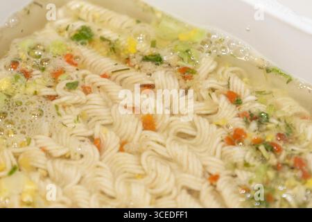 Spaghetti istantanei con spezie e acqua su una scatola di plastica bianca. Foto Stock