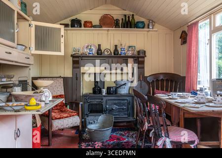 Un'antica cucina con oggetti storici e tavolo da cucina preparato per un pasto al St Fagans National Museum of History, Galles del Sud, Regno Unito Foto Stock