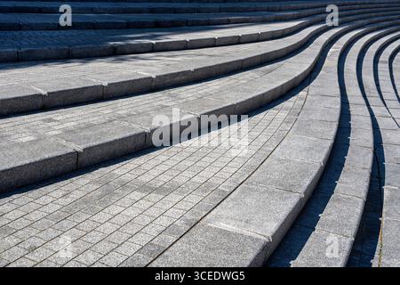 Scala in pietra curva con gradini uniformi e motivi geometrici alla luce del sole Foto Stock