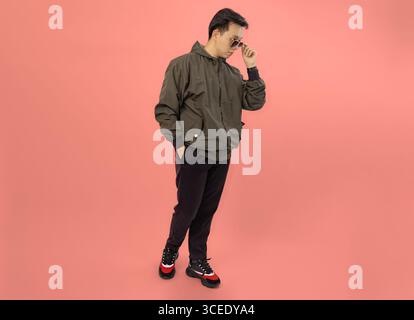 uomo elegante in una giacca casual che poggia su un solido sfondo corallino Foto Stock