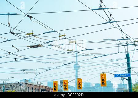 I cavi del tram attraversano Spadina al College con i semafori sottostanti e la Torre CN leggermente visibile nella foschia. Foto Stock