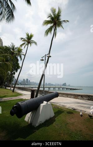 Un cannone nei giardini, che indica il mare di fronte all'Eastern & Oriental (e&o) Hotel nella città di Goerge, capitale di Penang in Malesia, il c Foto Stock