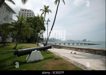 Un cannone nei giardini, che indica il mare di fronte all'Eastern & Oriental (e&o) Hotel nella città di Goerge, capitale di Penang in Malesia, il c Foto Stock