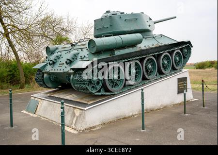 HORTOBAGY, UNGHERIA 23 APRILE 2022 Una vista dettagliata di un carro T 34 verde scuro esposto su un piedistallo in pietra all'aperto. Il carro armato è in primo piano Foto Stock