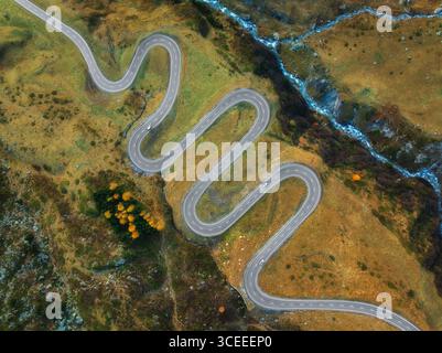 Vista aerea della tortuosa strada di montagna, fiume nella valle alpina Foto Stock