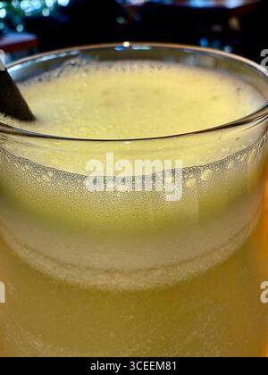 Una bevanda frizzante di giallo pallido servita in un bicchiere su un tavolo presso un ristorante, rinfrescante e fresca. Foto Stock