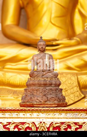 Il Buddha meditava con grazia su un fiore di loto con sfondo arancione. (Informazioni sul buddismo) Foto Stock