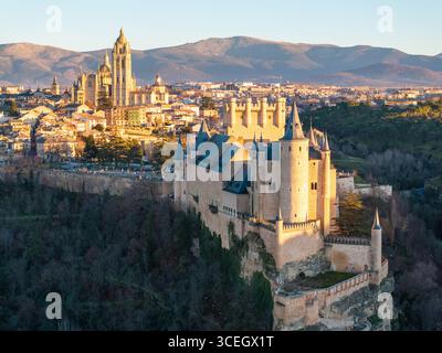 Vista aerea della Alcázar della formidabile sagoma in pietra di Segovia contro il soffice bagliore del sole nascente, giustapposto alla lontana cattedrale, se Foto Stock