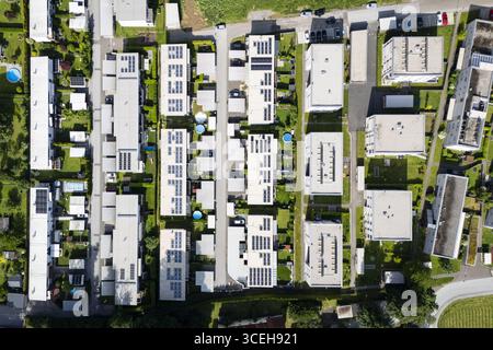 Vista aerea di file di edifici ben curati che crogiolano alla luce del sole, pannelli solari scintillanti, adagiati su una lussureggiante vegetazione in una vivace zona residenziale, Peggau-Deutschfeistritz, Stiria, Austria. Foto Stock