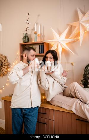 Una coppia accogliente si diverte con la cioccolata calda a casa Foto Stock