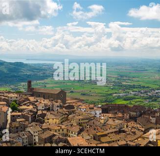 Veduta aerea dei tetti di terracotta che scendono lungo la collina, punteggiati dalla stoica presenza di un'antica chiesa, Cortona, Toscana, Italia. Foto Stock