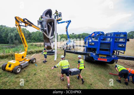 Londra, Regno Unito. 18 agosto 2025. Come parte di un aggiornamento della presentazione di sculture all'aperto, a metà della stagione estiva, la monumentale scultura (alta 7 metri, 6,7 tonnellate) grande forma verticale interna/esterna (1953-4, cast 1981-82) viene trasferita - Henry Moore Studios & Gardens, la casa dello scultore del XX secolo Henry Moore a Perry Green nell'Hertfordshire. Crediti: Guy Bell/Alamy Live News Foto Stock