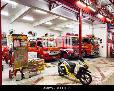 Tre camion dei vigili del fuoco rossi parcheggiati all'interno di una stazione dei vigili del fuoco malese con decorazioni culturali sulle pareti George Town Penang Malaysia motori dei vigili del fuoco malesi Foto Stock
