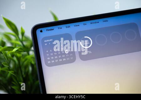Poznan, Polonia - 15 agosto 2025: Applicazione Finder su un computer portatile Apple con macOS 26 con Liquid Glass, che visualizza il calendario e il widget della batteria Foto Stock