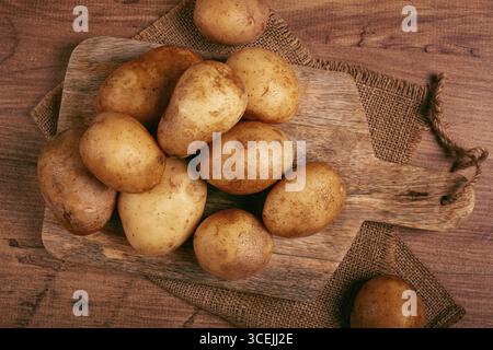 Patate crude, sparse su un tagliere, primo piano, nessuna gente Foto Stock
