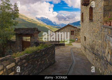 Vicolo in pietra nel villaggio di montagna di Fanlo, con case rustiche e viste panoramiche della verde valle di Ordesa in Aragona, Pirenei spagnoli. Foto Stock